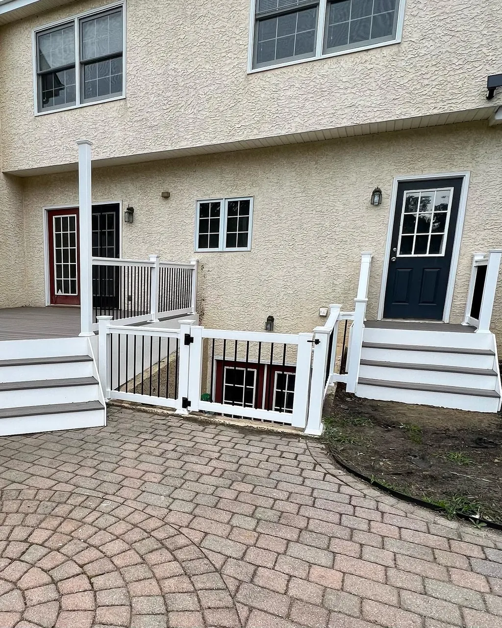 White railing and gate beside a paver courtyard